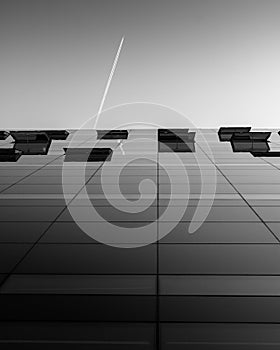 The glass facade of the Royal Library/the Black Diamond, Copenhagen, with the trail of a plane above.