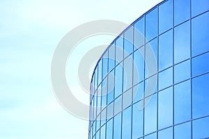 The glass facade of a skyscraper with a mirror reflection of sky windows