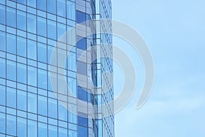 The glass facade of a skyscraper with a mirror reflection of sky windows