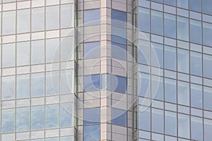 The glass facade of a skyscraper with a mirror reflection of sky windows