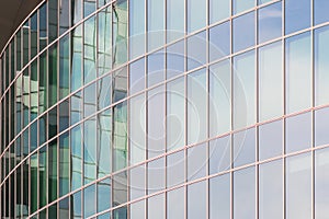 The glass facade of a skyscraper with a mirror reflection of sky windows