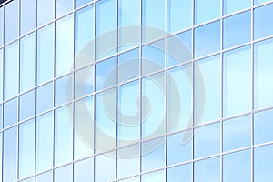 The glass facade of a skyscraper with a mirror reflection of sky windows