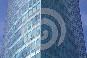 The glass facade of a skyscraper with a mirror reflection of sky windows