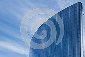 The glass facade of a skyscraper with a mirror reflection of sky windows