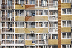 A glass facade with windows of a brick apartment building with loggias and balconies. Condominium with air conditioning