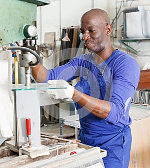 glass factory worker drilling bores in glass