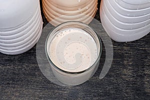 Glass of fermented milk drink against plastic bottles, top view