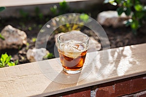 Glass filled with ice and a refreshing drink on a wallflower on the outdoor terrace on a summer afternoon. photo