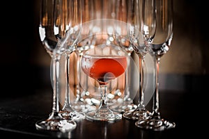 Glass filled with tasty red summer alcoholic drink with empty champagne glasses