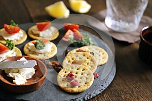 A Glass filled with whiskey soda and Appetizers crackers, dried fruit, tomatoes, parsley, and cream cheese