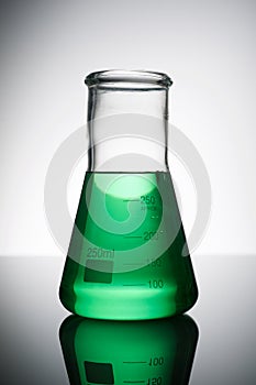 Glass flask placed in a laboratory table with green liquid