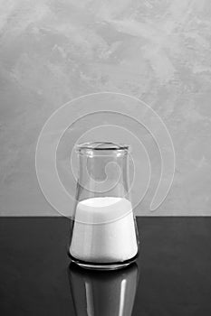 Glass flask with white chemistry powder. Sodium chlorate is a white crystalline powder, used for applications in bleaching pulp to photo