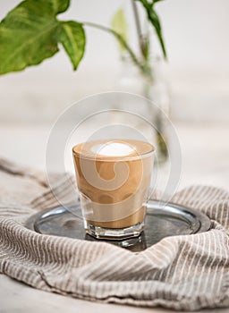 Glass of flat white coffee with heart shaped foam milk