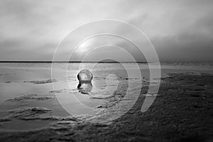 Glass Float Resting in Wet Sand at Sunrise -- Black and White