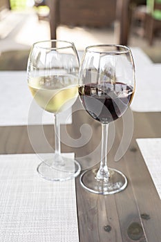 a glass of fragrant white and a glass of ruby red wine on a wooden table in a restaurant