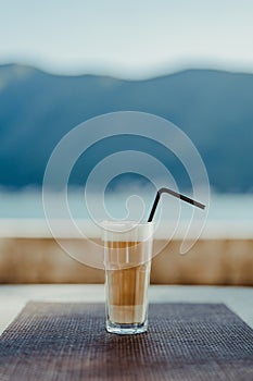 Glass of frappe with a straw on a table in a cafe photo