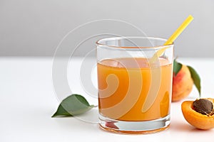 Glass of fresh apricot juice with yellow straw
