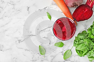 Glass of fresh beet juice and vegetables on table