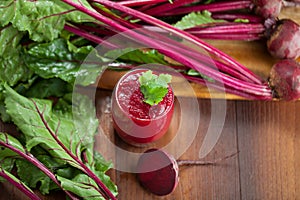 Glass of fresh beetroot juice with bets on wooden table.