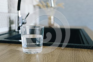 Glass of fresh cold water on table in kitchen