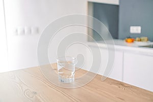 Glass of fresh cold water on table in kitchen. Space for text