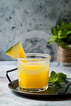 Glass of fresh golden watermelon juice or smoothie with slices of watermelon. Refreshing cold summer fruit drink.