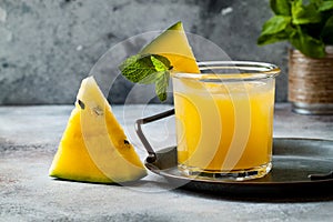 Glass of fresh golden watermelon juice or smoothie with slices of watermelon. Refreshing cold summer fruit drink.