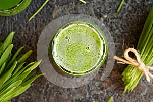 A glass of fresh green barley grass juice with barleygrass blades