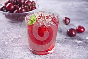 Glass with fresh homemade cherry sweet iced tea or cocktail, lemonade with mint. Refreshing cold drink. Summer party