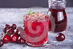 Glass with fresh homemade cherry sweet iced tea or cocktail, lemonade with mint. Refreshing cold drink. Summer party