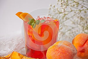 Glass with fresh homemade peach sweet iced tea or cocktail, lemonade with mint. Refreshing cold drink. Summer party