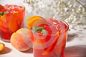 Glass with fresh homemade peach sweet iced tea or cocktail, lemonade with mint. Refreshing cold drink. Summer party.