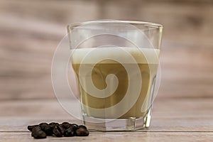 Glass of fresh iced coffee and coffee beans on a wooden table