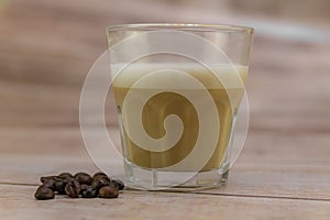 Glass of fresh iced coffee and coffee beans on a wooden table