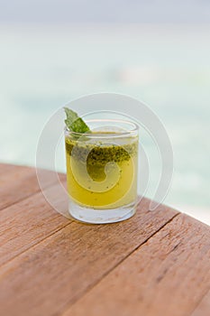 Glass of fresh juice or cocktail on table at beach