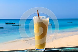 Glass of fresh juice by ocean. Tropical vacations concept
