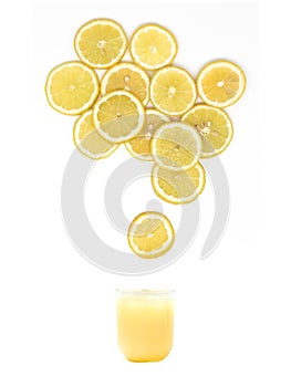 Glass with fresh lemon juice is standing under many lemon slices on white background