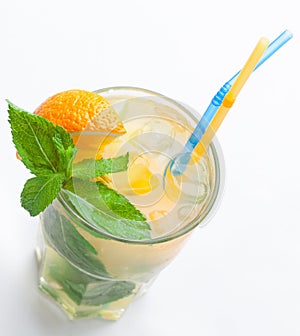 Glass of fresh lemonade with orange, ice cubes, mint, straws