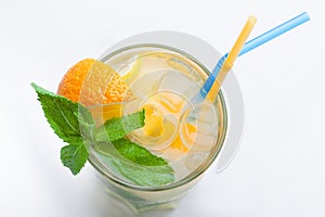 Glass of fresh lemonade with orange, ice cubes, mint, straws