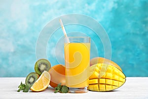Glass with fresh mango juice and tasty fruits