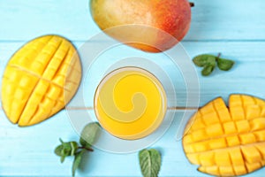 Glass with fresh mango juice and tasty fruits on wooden table