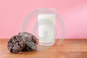 Glass of fresh milk with crunchy baked chocolate sugar cookies on wooden table with