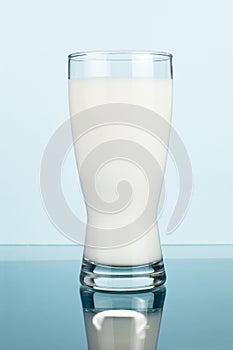 Glass of fresh milk on a dark cyan