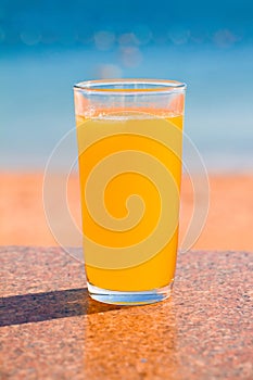 Glass of Fresh orange juice on blue sea background