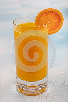 Glass of fresh orange juice with fresh fruits on wooden table