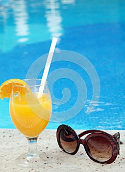 Glass of fresh orange juice near the pool