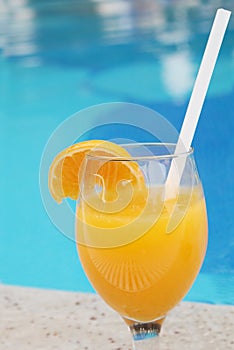 Glass of fresh orange juice near the pool