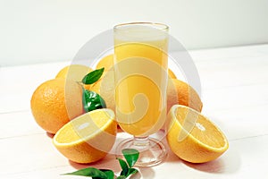 A glass of fresh orange juice and orange fruits on a wooden table. Healthy food