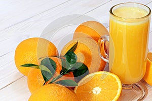 A glass of fresh orange juice and orange fruits on a wooden table. Healthy food