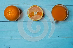 A glass of fresh orange juice with sliced oranges on a wooden table. Preparation of fresh orange juice